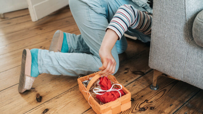 little girl looking for hidden gifts under the sofa in living room