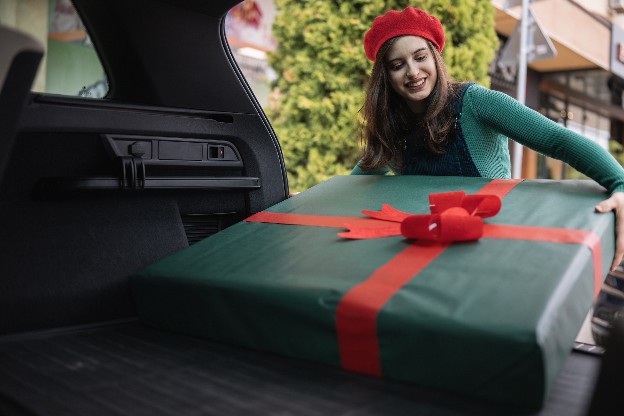 woman hiding a big present in the trunk of her car