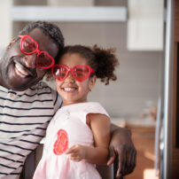 Mixed race Father and daughter taste lollipop during Valentine’s Day