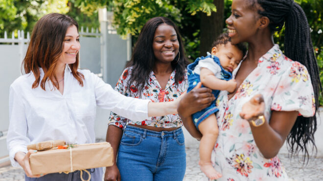 Group of three women celebrating newborn baby in a garden party.