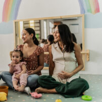 Mothers talking while their babies playing in a support group therapy on a playroom