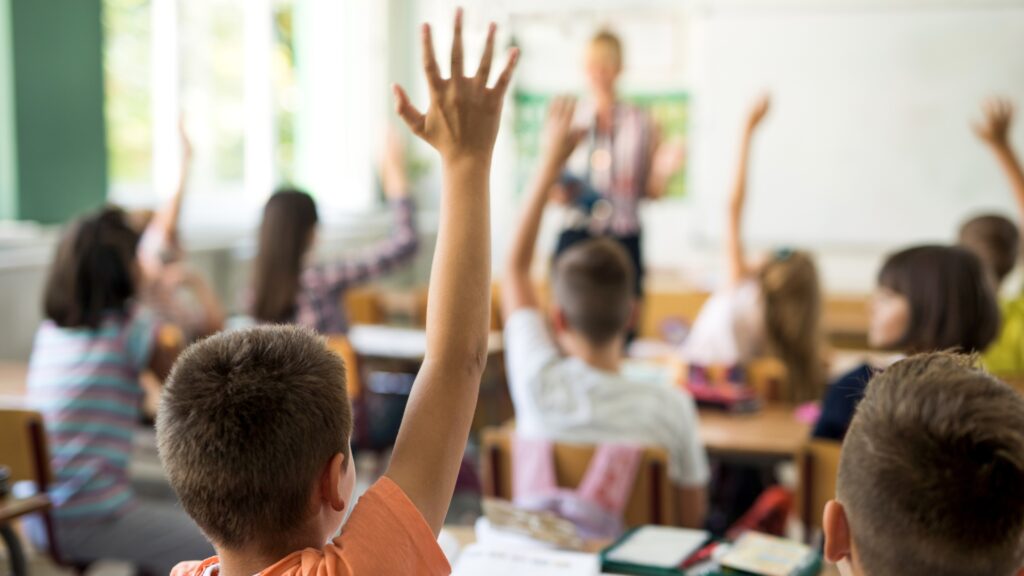 Students raise their hand in a classroom