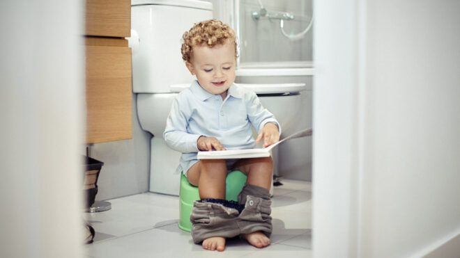 child sitting on potty and reading