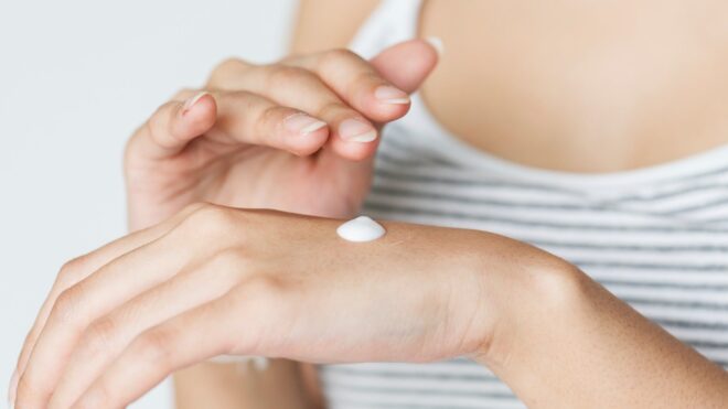 WOMAN APPLYING LOTION TO HER  HANDS
