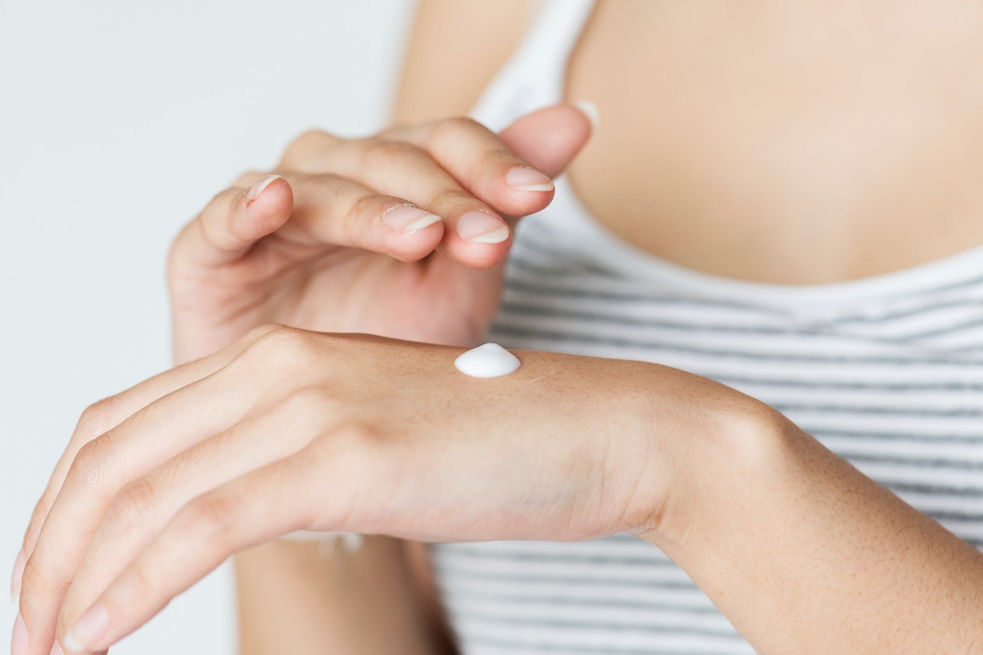 WOMAN APPLYING LOTION TO HER HANDS