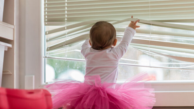 baby playing with corded blinds
