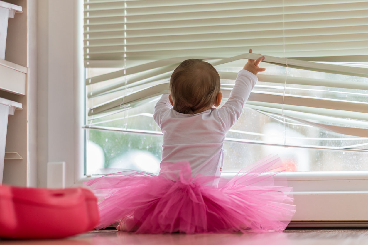 baby playing with corded blinds