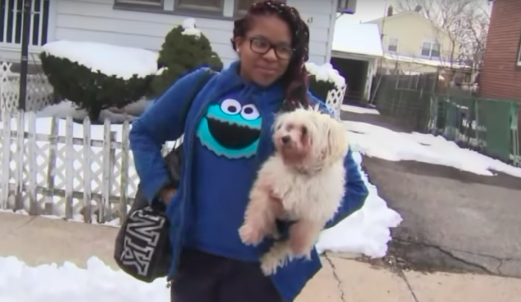 Teen Kayla Rose poses while smiling and holding up her small dog.
