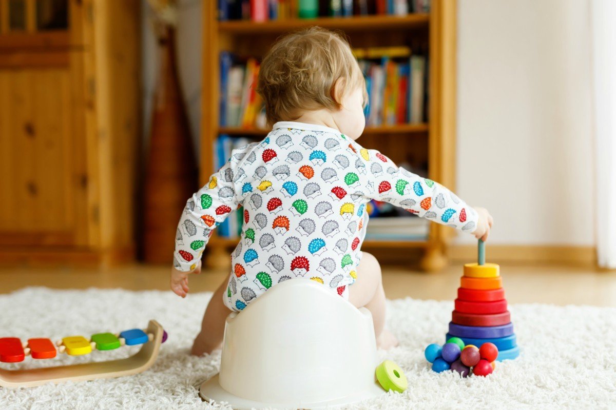 Back view of baby boy sitting in a Bumbo chair playing with toys.