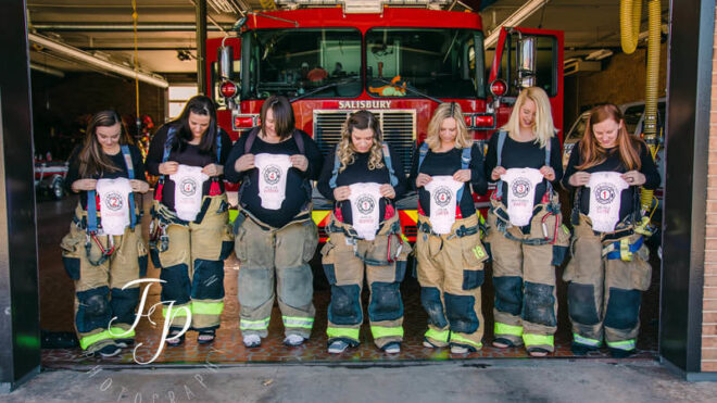 Seven firefighter wives from the Salisbury Fire Department pose with onesies.