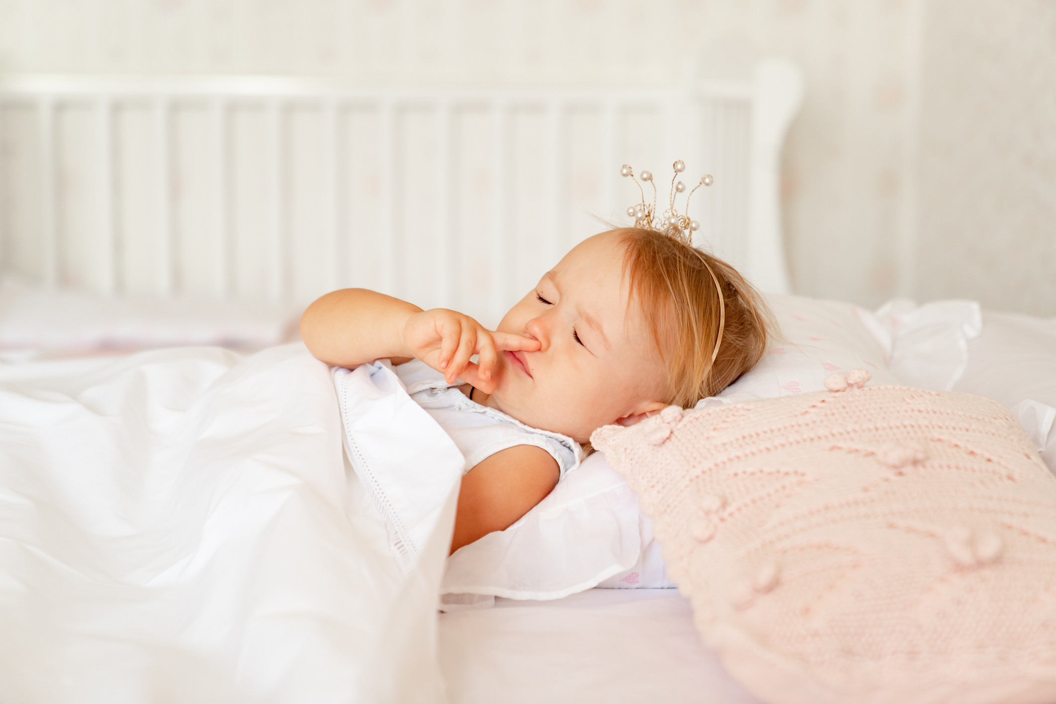 little girl sleeping in bed with crown on head. Princess birthday party.