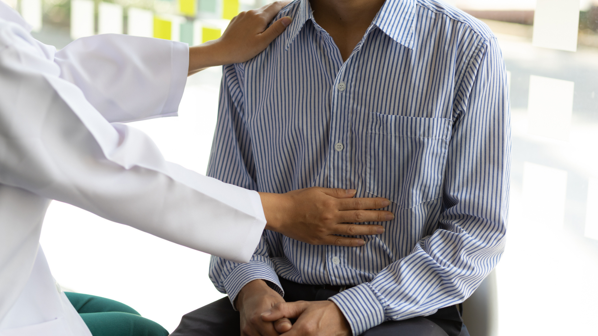 a doctor's arms on a man's shoulder and stomach