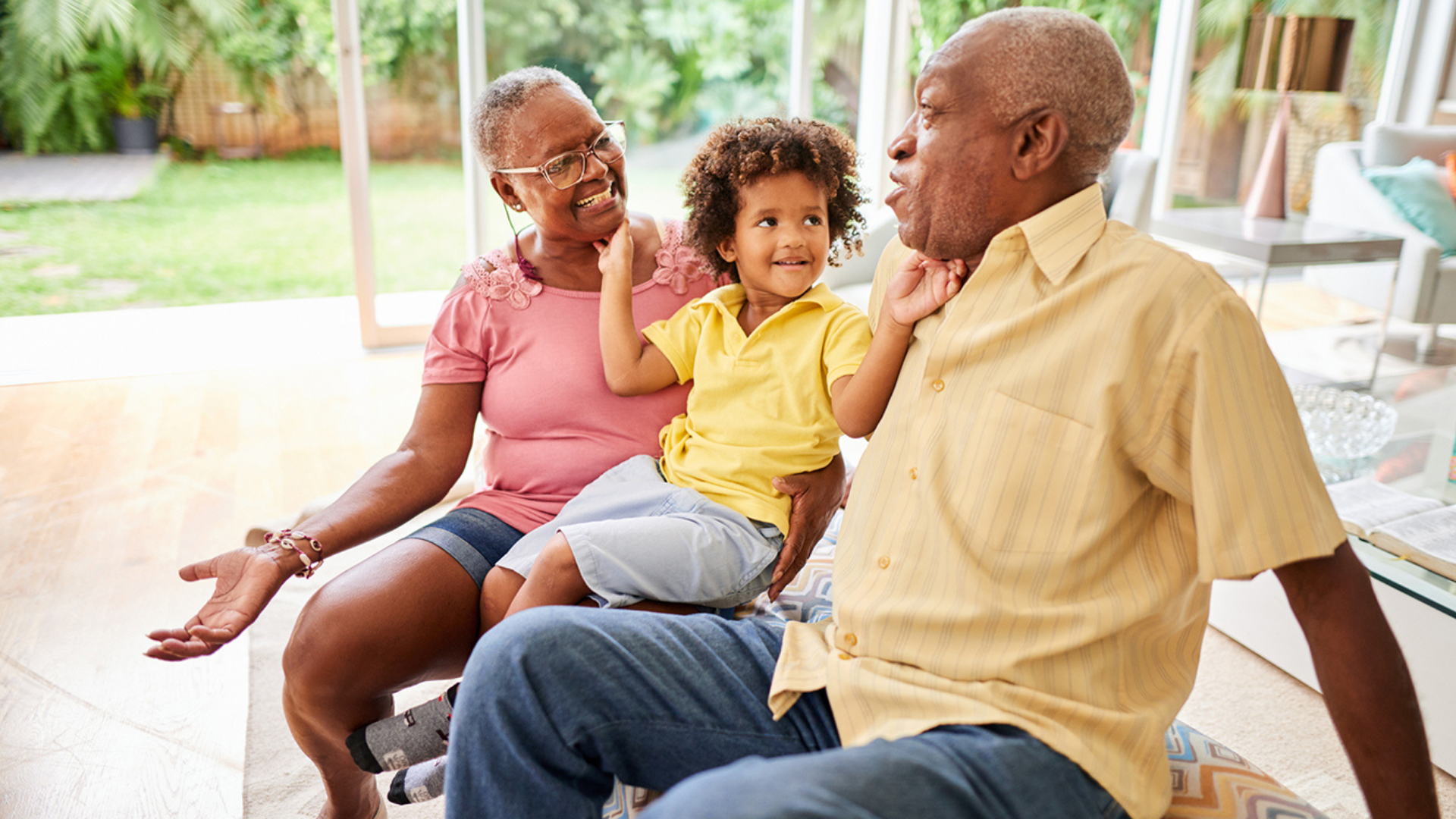 black grandparents and their black grandchild tickling their faces