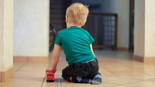 Little boy plays alone on kitchen floor