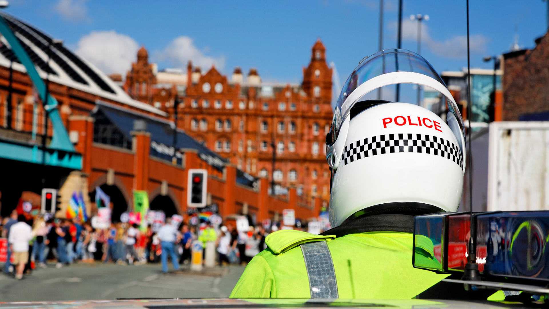 UK police in riot gear standing a distance away from people protesting