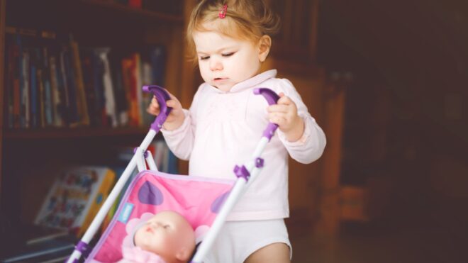 Walking toddler pushing toy stroller