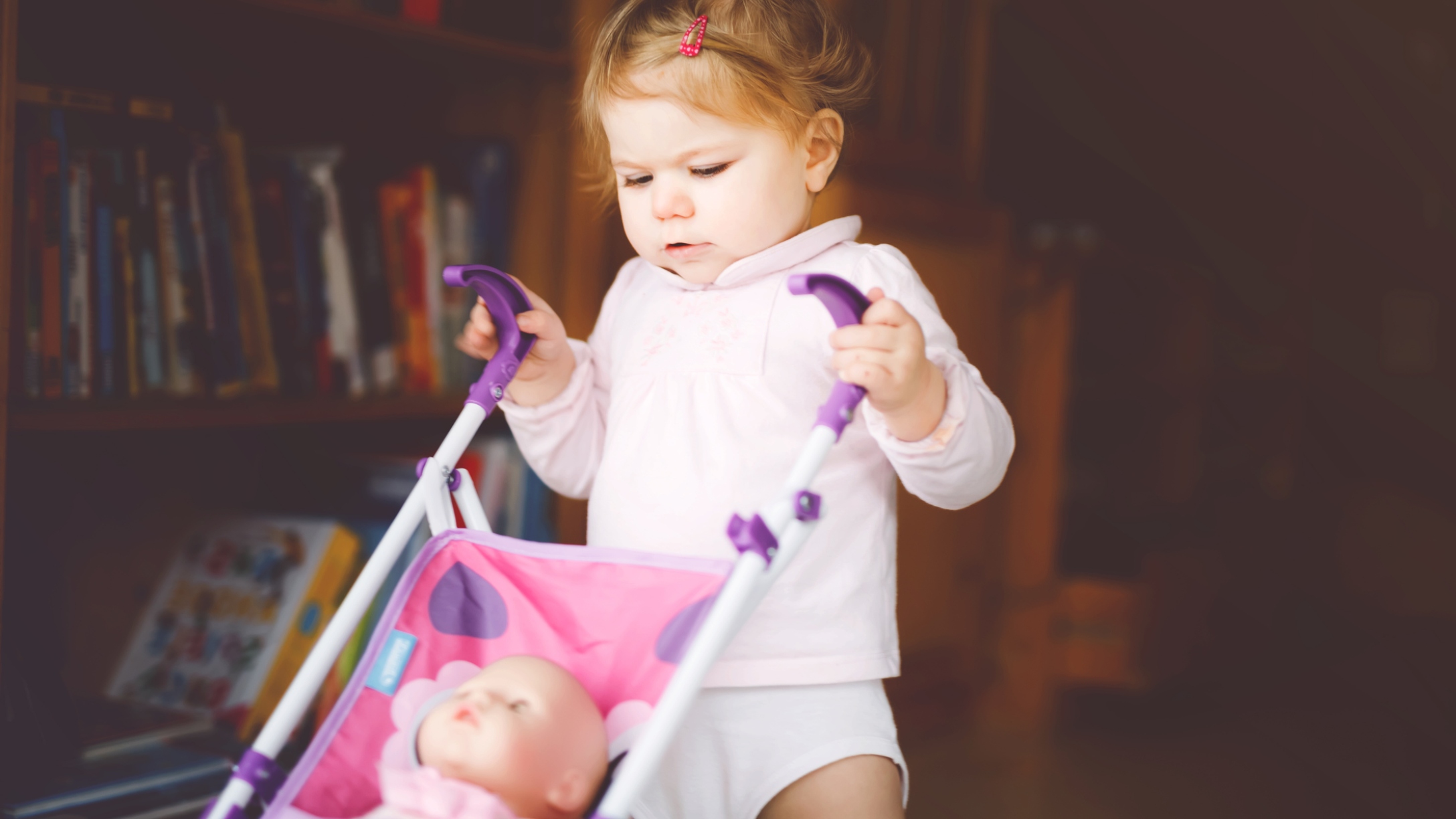 Walking toddler pushing toy stroller