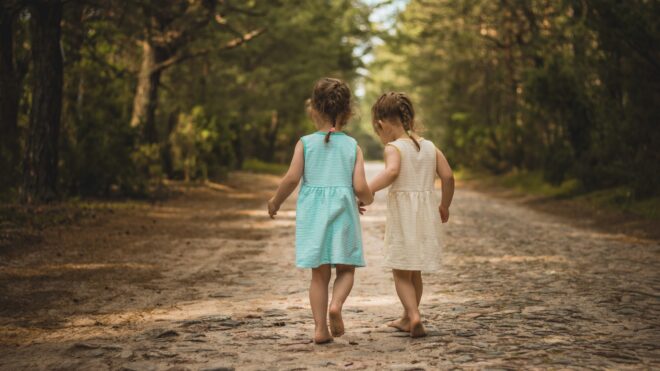 Twin girls walking down dirt road