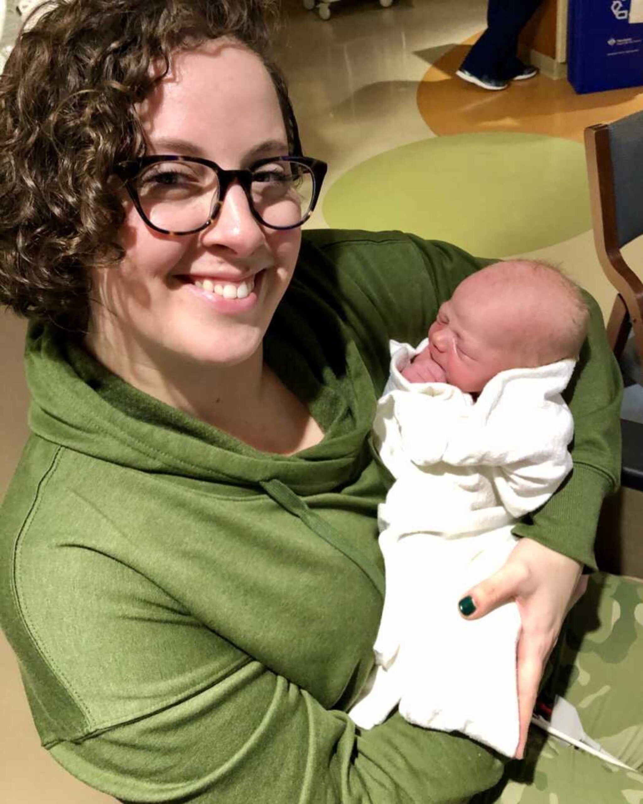 adoptive-mom-in-green-sweater-holding-newborn-son-900x1125-1.jpeg