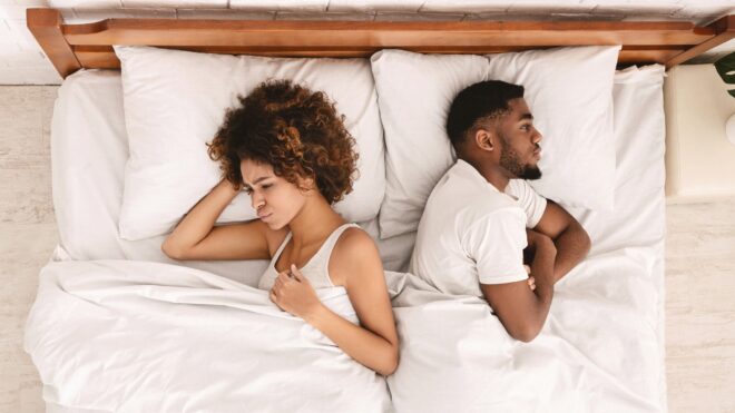 african-american couple ignoring each other in bed