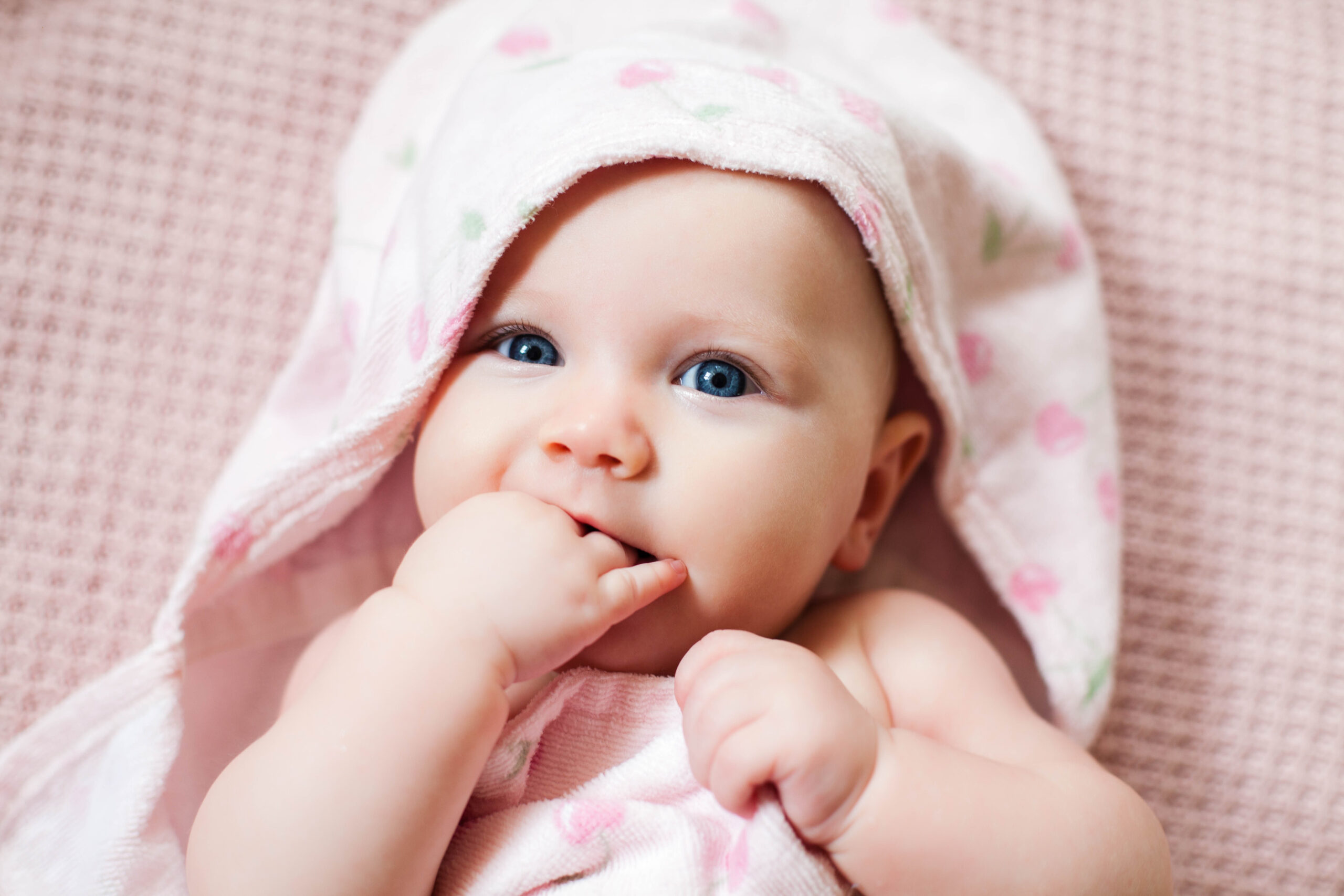 Authentic portrait of 4 months baby girl wrapped in towel after bath.