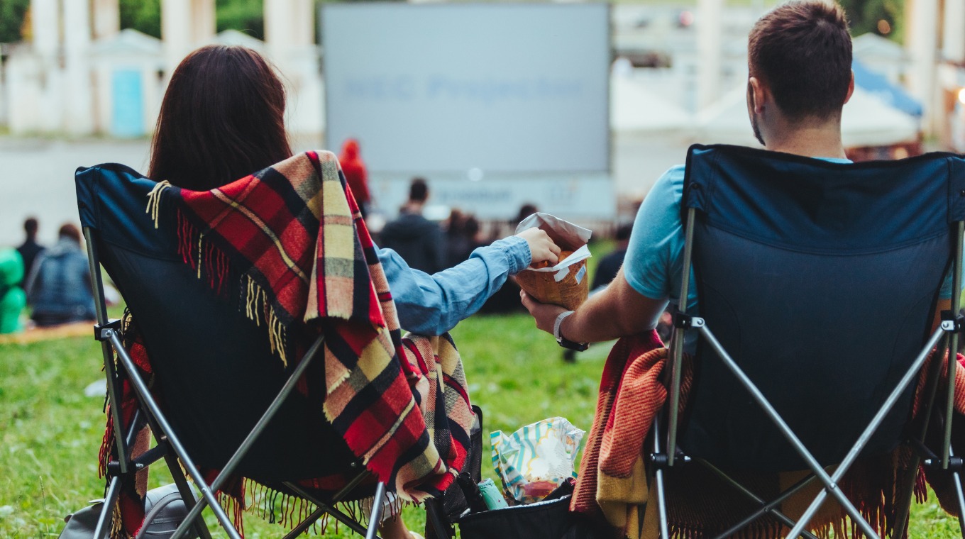 couple-sitting-in-campchairs-in-city-park-looking-movie-outdoors-at-picture-id1166556194.jpg