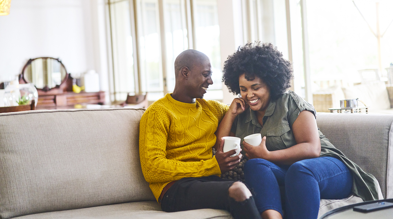 Couple talking and laughing together over coffee at home