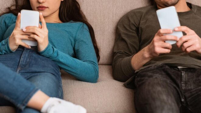 couple using cell phones sitting on the couch