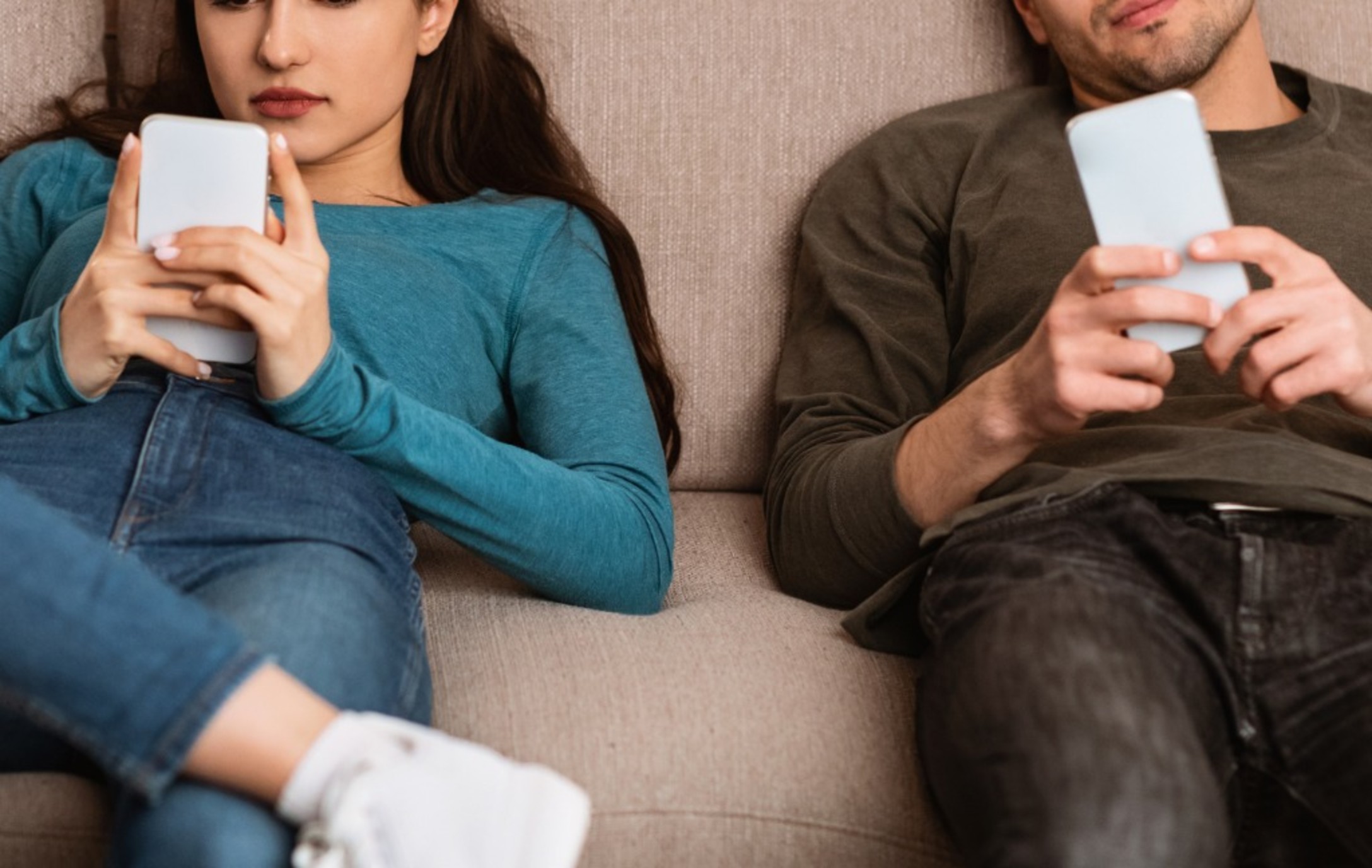 couple using cell phones sitting on the couch