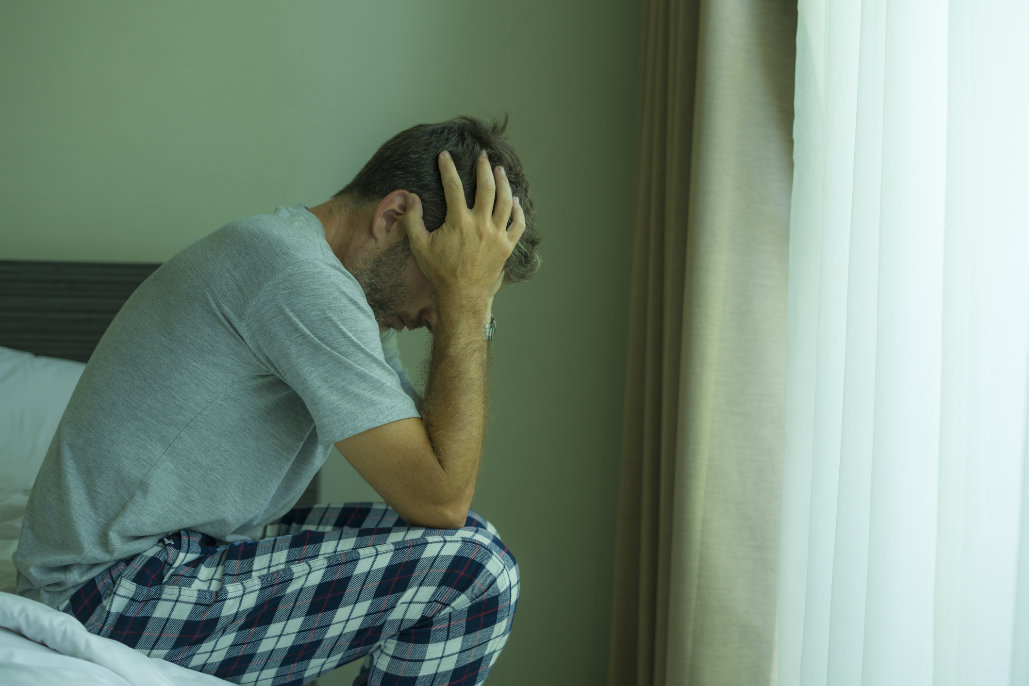 dramatic portrait of attractive scared and depressed 40s man on bed in pajamas feeling worried suffering anxiety and depression problem during virus quarantine home lockdown