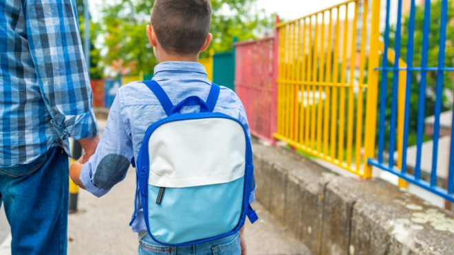 Child with a backpack holding dad's hand