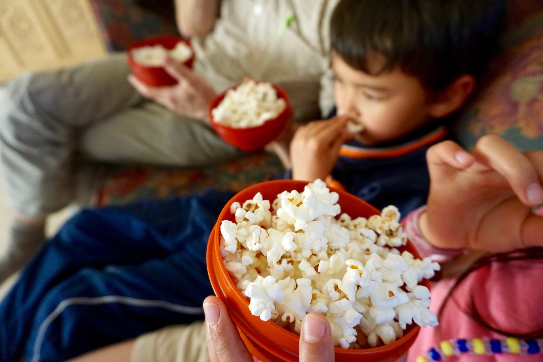 family-of-three-eating-popcorn-while-sitting-on-couch-watching-tv_t20_z9Anon.jpg