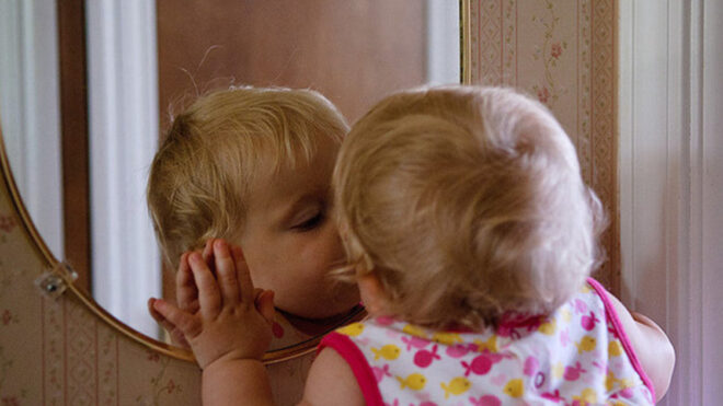 baby kissing herself in a mirror