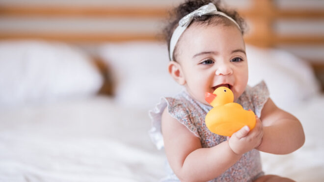 baby with rubber ducky in bed