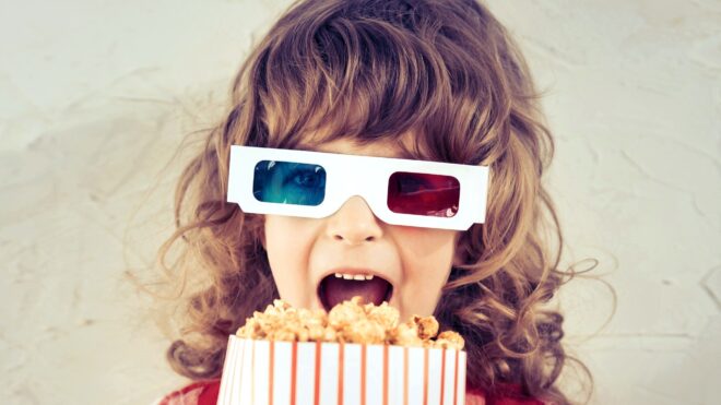 Cute girl watching movie with 3D glasses and popcorn