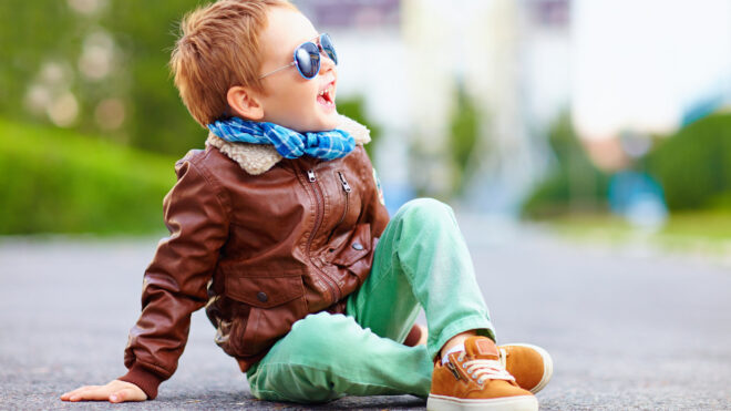 Happy boy in leather jacket posing on the ground