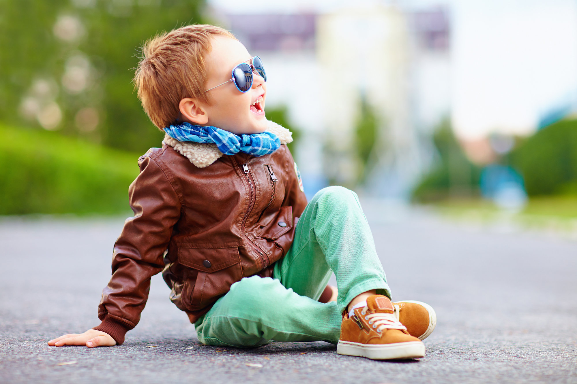 Happy boy in leather jacket posing on the ground