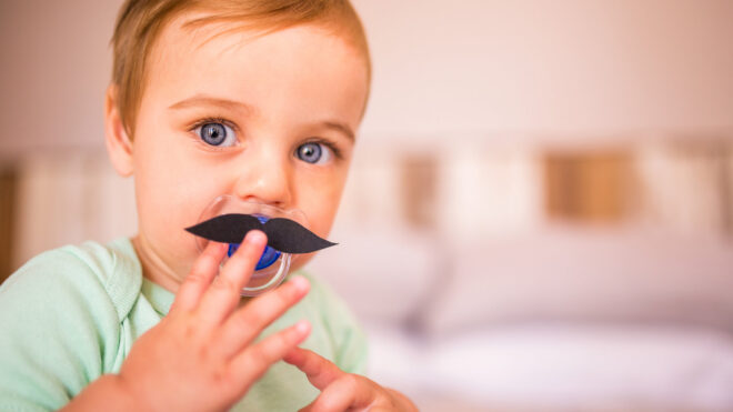 little boy holding up fake mustache