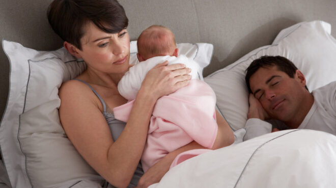 mom awake with baby while dad sleeps