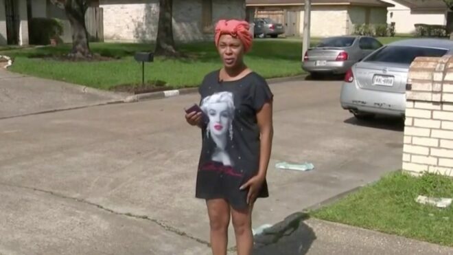 Joselyn Lewis stands at the edge of her driveway in her T-shirt dress and red headscarf.