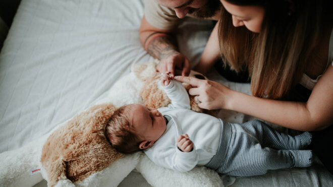 Two parents stand over their newborn