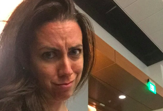 Michelle Solone makes an unhappy face while breastfeeding her daughter in a lecture hall.