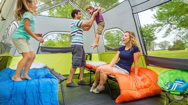 A family sits inside a large multi-person tent with a see-through roof and walls.