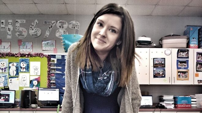 Jessica Gentry sits on a desk in her classroom