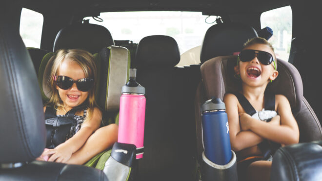 Kids happily sit in the backseat of a car