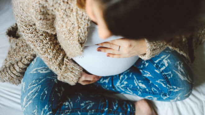 Pregnant woman sitting on bed