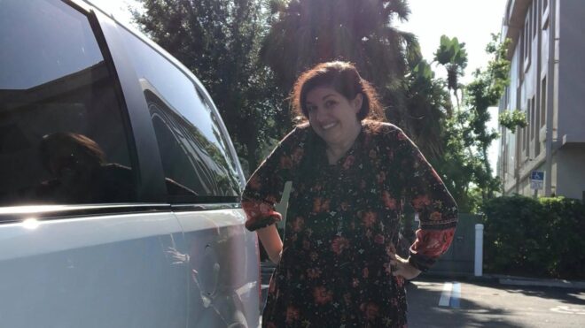 Mary Katherine Backstrom smiles for the camera while standing next to her minivan