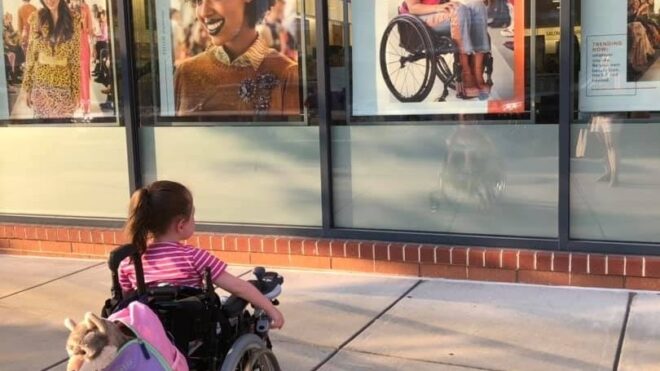 Maren Anderson sits in her wheelchair looking at an Ulta beauty store ad
