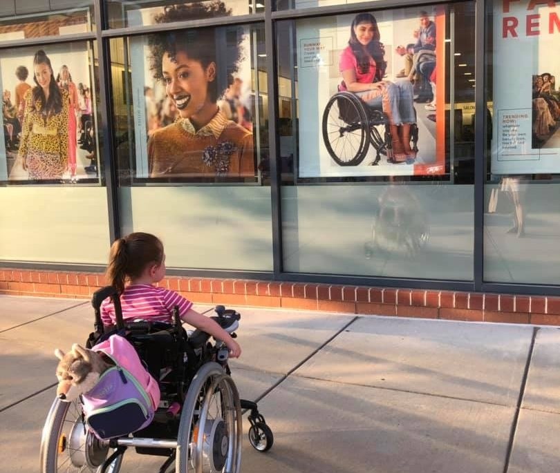 Maren Anderson sits in her wheelchair looking at an Ulta beauty store ad