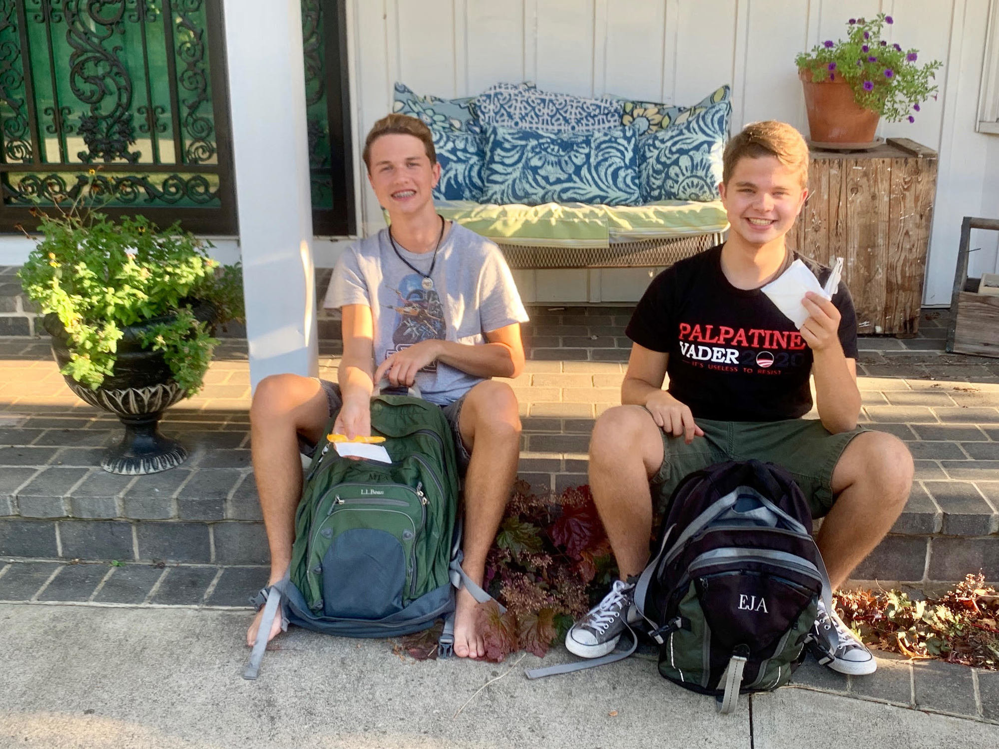 Tara Epple Ahrens's sons hold up period supplies out of their backpacks